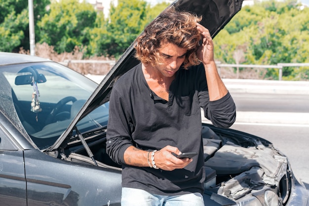 Jeune homme de race blanche essayant de réparer une panne dans sa voiture