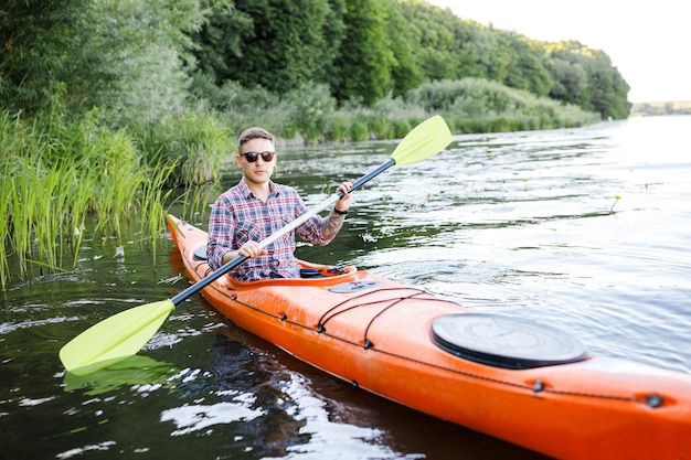 Un jeune homme de race blanche est assis dans un kayak et des pagaies Le concept de divertissement aquatique