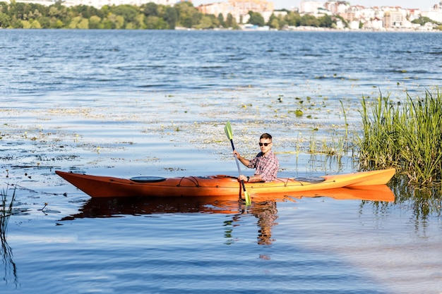 Un jeune homme de race blanche est assis dans un kayak et des pagaies Le concept de divertissement aquatique