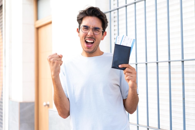 Jeune homme de race blanche à l'extérieur heureux en vacances avec passeport et billets d'avion