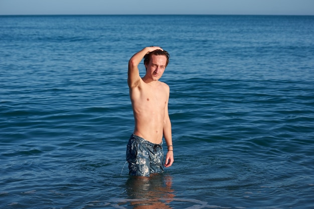 Un jeune homme de race blanche en forme de toucher ses cheveux dans la mer