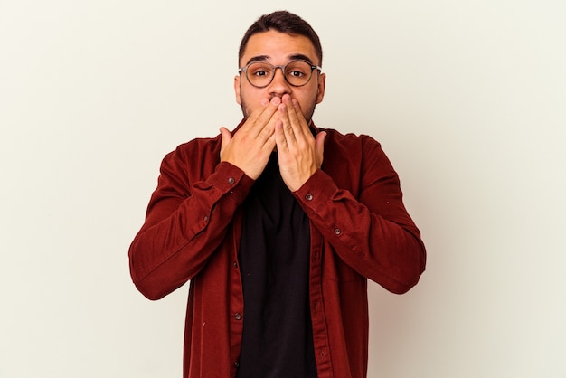 Jeune homme de race blanche isolé sur fond blanc choqué couvrant la bouche avec les mains.