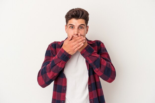 Jeune homme de race blanche isolé sur fond blanc couvrant la bouche avec les mains à l'air inquiet.