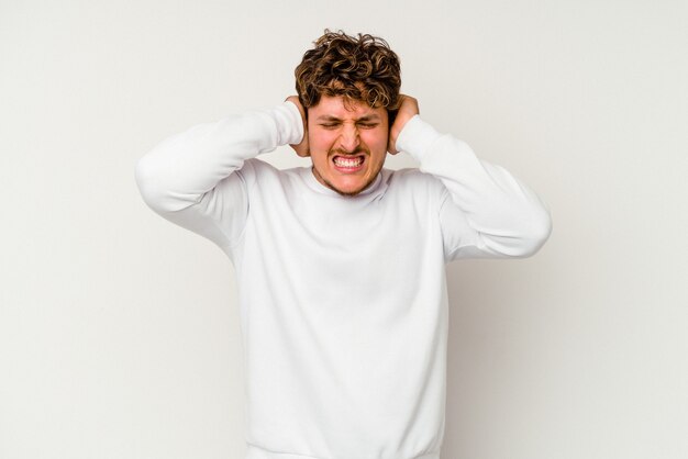 Jeune homme de race blanche isolé sur fond blanc couvrant les oreilles avec les mains.