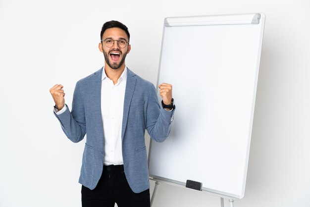 Jeune homme de race blanche isolé sur fond blanc donnant une présentation sur un tableau blanc et célébrant une victoire