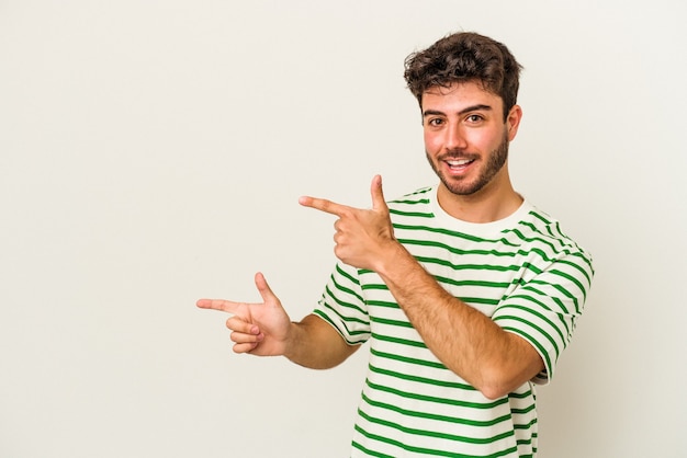 Jeune homme de race blanche isolé sur fond blanc excité pointant avec les index loin.