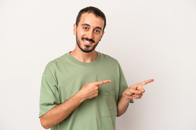 Jeune homme de race blanche isolé sur fond blanc excité pointant avec les index loin.