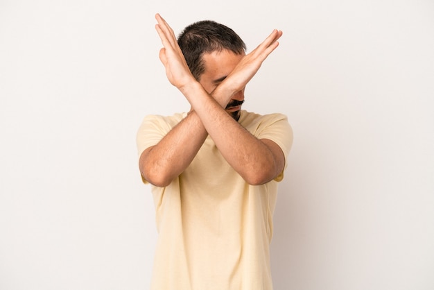 Jeune homme de race blanche isolé sur fond blanc en gardant les deux bras croisés, concept de déni.