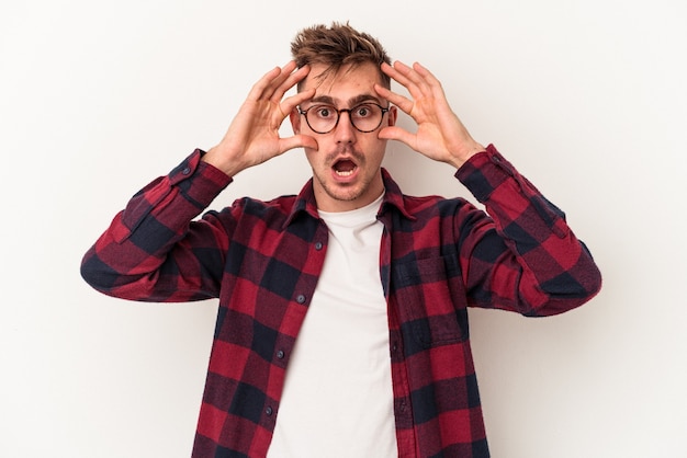 Jeune homme de race blanche isolé sur fond blanc en gardant les yeux ouverts pour trouver une opportunité de réussite.