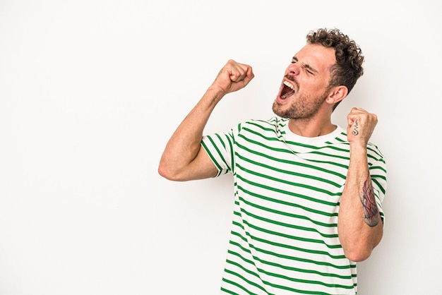 Jeune homme de race blanche isolé sur fond blanc levant le poing après une victoire, concept gagnant.