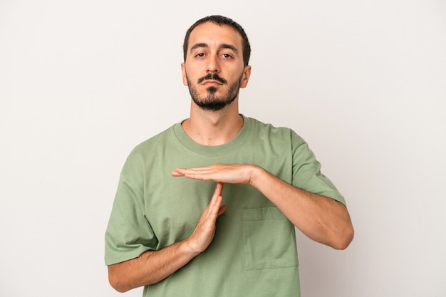 Jeune homme de race blanche isolé sur fond blanc montrant un geste de délai d'attente.