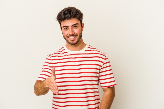 Jeune homme de race blanche isolé sur fond blanc s'étendant la main à la caméra en geste de salutation.