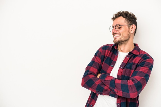 Jeune homme de race blanche isolé sur fond blanc souriant confiant avec les bras croisés.