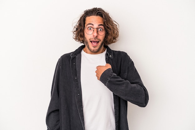 Jeune homme de race blanche isolé sur fond blanc surpris en pointant avec le doigt, souriant largement.