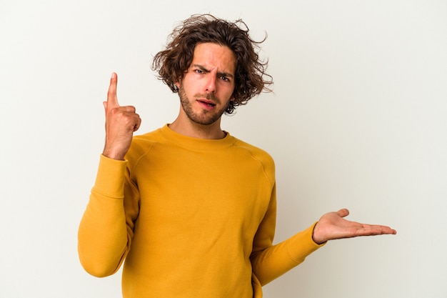 Jeune homme de race blanche isolé sur fond blanc tenant et montrant un produit à portée de main.