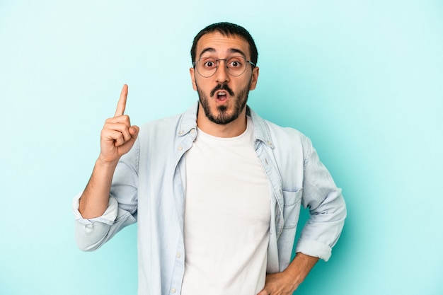 Jeune homme de race blanche isolé sur fond bleu ayant une idée, concept d'inspiration.