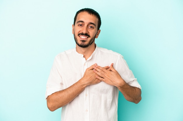 Jeune homme de race blanche isolé sur fond bleu a une expression amicale, appuyant la paume sur la poitrine. Notion d'amour.