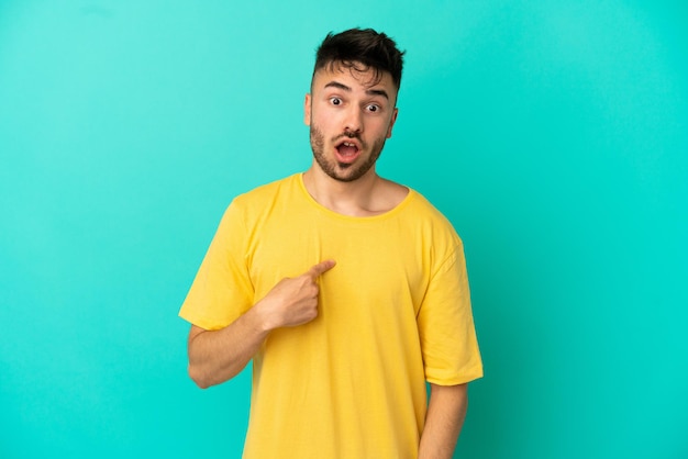 Jeune homme de race blanche isolé sur fond bleu avec une expression faciale surprise