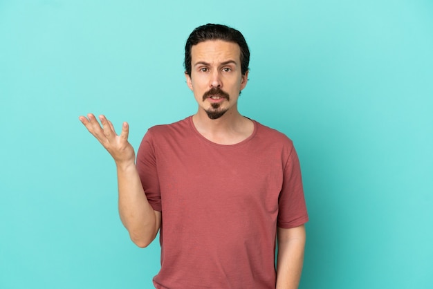 Photo jeune homme de race blanche isolé sur fond bleu faisant des doutes geste