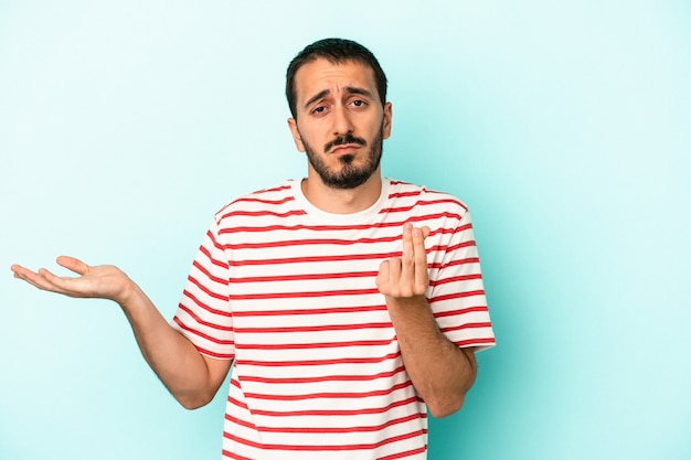 Jeune homme de race blanche isolé sur fond bleu montrant qu'elle n'a pas d'argent.