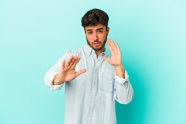 Jeune homme de race blanche isolé sur fond bleu rejetant quelqu'un montrant un geste de dégoût.