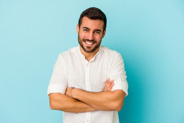 Jeune homme de race blanche isolé sur fond bleu en riant et en s'amusant.