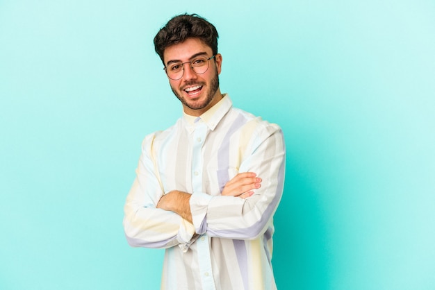 Jeune homme de race blanche isolé sur fond bleu en riant et en s'amusant.