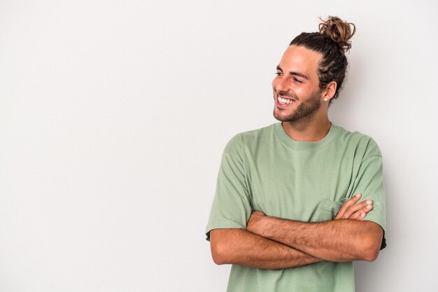 Jeune homme de race blanche isolé sur fond gris souriant confiant avec les bras croisés.