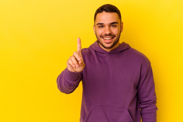 Jeune homme de race blanche isolé sur fond jaune montrant le numéro un avec le doigt.