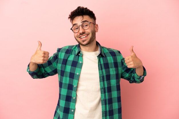 Jeune homme de race blanche isolé sur fond rose donnant un coup de pouce geste