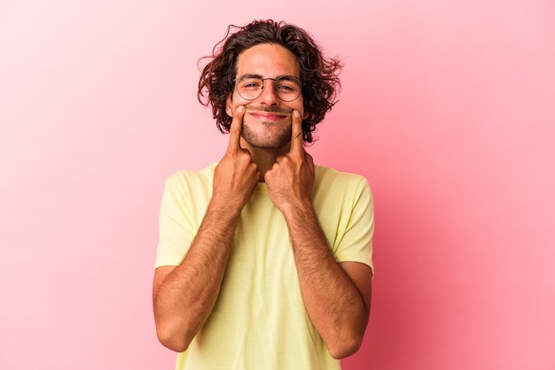 Jeune homme de race blanche isolé sur fond rose doutant entre deux options.