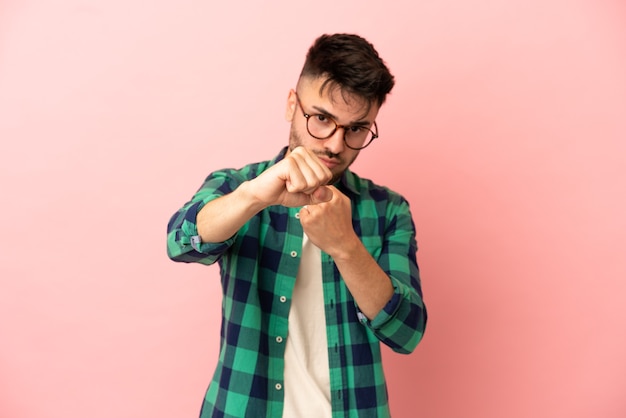 Jeune homme de race blanche isolé sur fond rose avec geste de combat