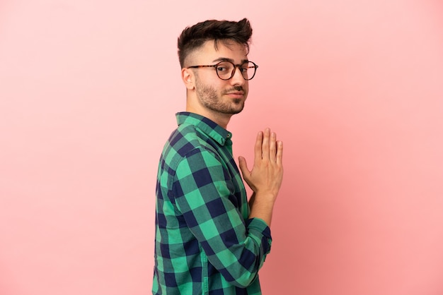 Jeune homme de race blanche isolé sur fond rose intrigant quelque chose