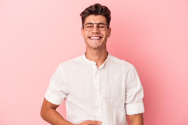 Un jeune homme de race blanche isolé sur fond rose touche le ventre, sourit doucement, mange et satisfait le concept.