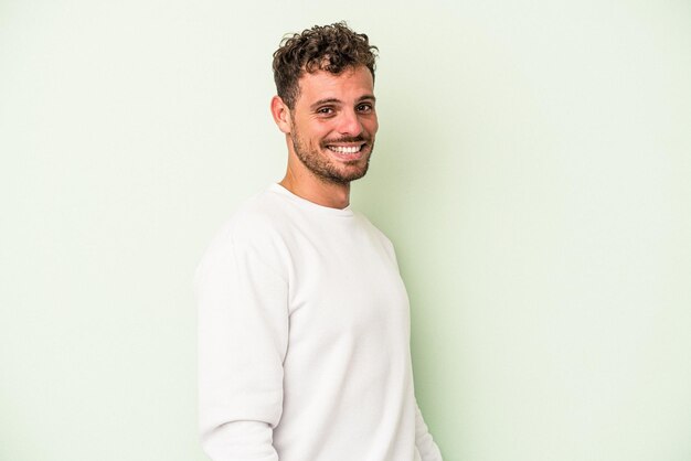 Jeune homme de race blanche isolé sur fond vert confiant en gardant les mains sur les hanches.