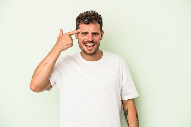 Jeune homme de race blanche isolé sur fond vert montrant un geste de déception avec l'index.