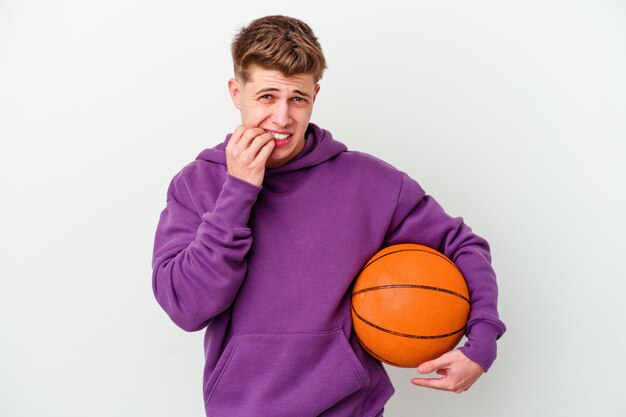 Jeune homme de race blanche jouant au basket-ball fond isolé se ronger les ongles, nerveux et très anxieux.