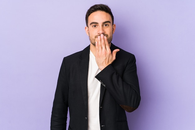 Jeune homme de race blanche sur le mur violet choqué, couvrant la bouche avec les mains