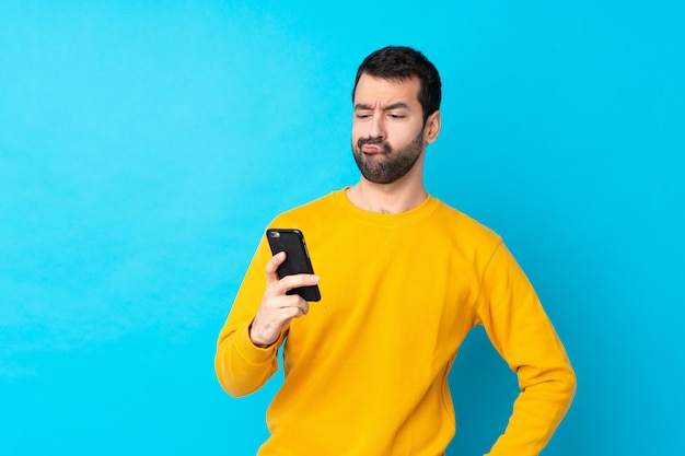 Jeune homme de race blanche sur la pensée de mur bleu isolé et l'envoi d'un message