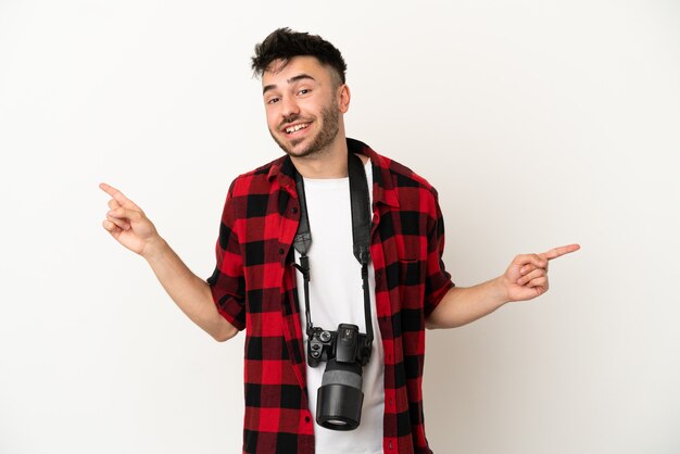 Jeune homme de race blanche photographe isolé sur fond blanc doigt pointé vers les latéraux et heureux