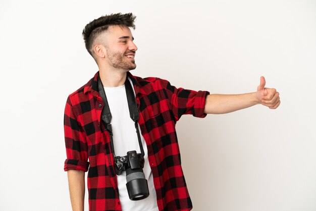 Jeune homme de race blanche photographe isolé sur fond blanc donnant un coup de pouce geste