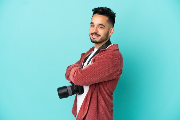 Jeune homme de race blanche photographe isolé sur fond bleu avec les bras croisés et avec impatience