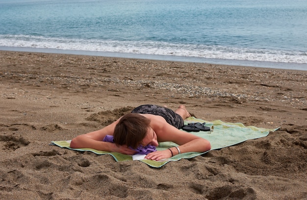 Un jeune homme de race blanche portant sur une serviette sur une plage