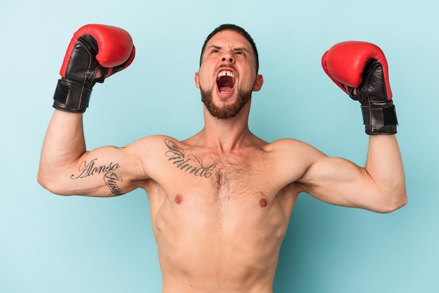 Jeune homme de race blanche pratiquant la boxe isolé sur fond bleu