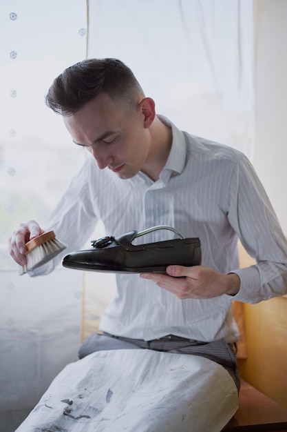 Jeune homme de race blanche réparant de vieilles chaussures en cuir pour hommes.