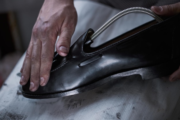 Jeune homme de race blanche réparant de vieilles chaussures en cuir pour hommes.