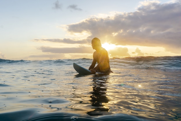 Jeune homme de race blanche se lever tôt pour faire du surf au lever du soleil