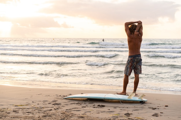 Jeune homme de race blanche se lever tôt pour faire du surf au lever du soleil