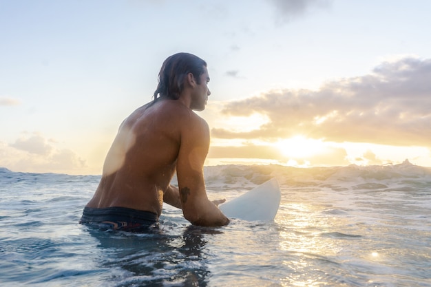 Jeune homme de race blanche se lever tôt pour faire du surf au lever du soleil