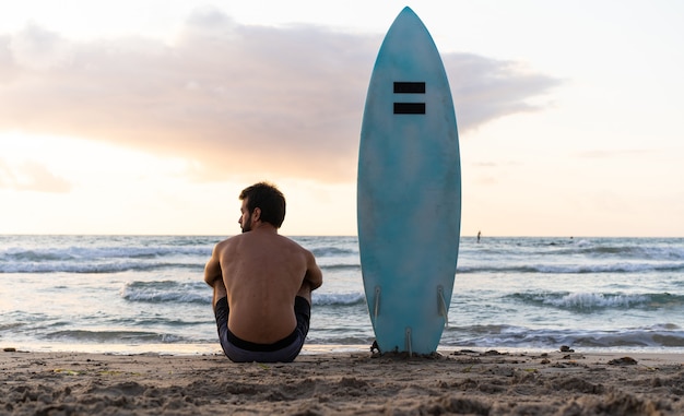 Jeune homme de race blanche se lever tôt pour faire du surf au lever du soleil